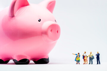 Miniature people. Two adults showing giant piggy bank to a boy