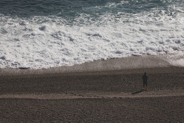 a lonely fisherman fishing on the beach