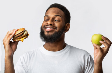 Black Guy Holding Burger And Apple Choosing Food, White Background