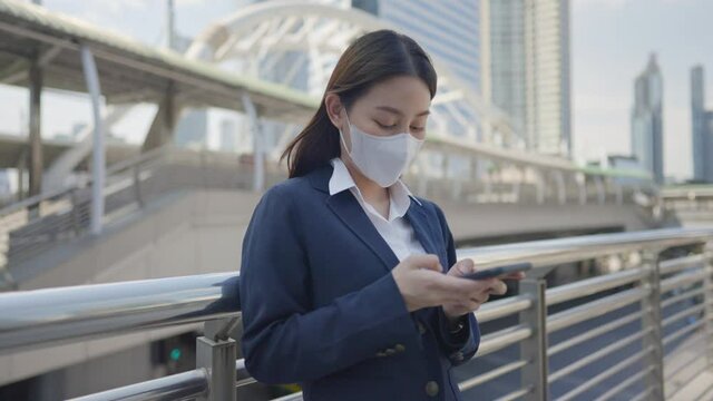 Adult Asian Business Woman Wear Medical Face Mask Texting Message On Phone Outdoor In The City Background