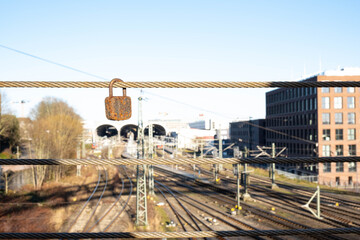 Naklejka premium rusty lock hangs on the iron cable of the bridge, above the railway