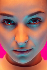 Close up caucasian woman's portrait isolated on pink studio background in mixed neon light....