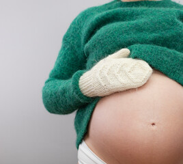 Pregnant woman in a woolen sweater and warm mittens