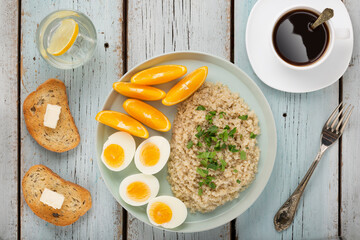 Healthy breakfast oatmeal, eggs, oranges on a blue wooden background, top view
