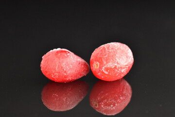 Two berries sweet and sour freshly frozen cranberries, close-up, black background.
