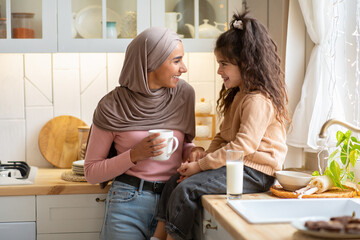 Cheerful muslim mother and her little daughter spending time in kitchen together