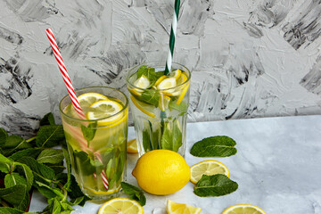 Refreshing drinks for summer, cold sweet and sour lemonade juice in the glasses with sliced fresh lemons. Refreshing summer drink. Traditional lemonade with lemon, mint and ice. Selective focus