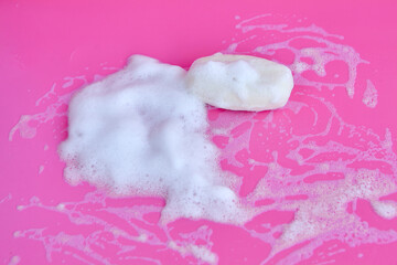 Washing concept. Foam bubbles and brick of soap on pink background. Cleaning service