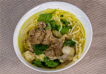 Top view of a plate of homemade soup with meat and noodles