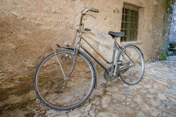 Fototapeta na wymiar View of forgotten old bike parked against the wall in one of the empty stone streets of an abandoned mountain village
