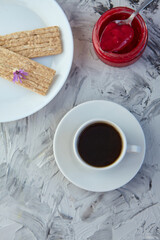 Crispbread with jam for Breakfast on a gray background. A jar of Fresh Honey with foam is next to a Cup of coffee. A minimum of calories. proper nutrition