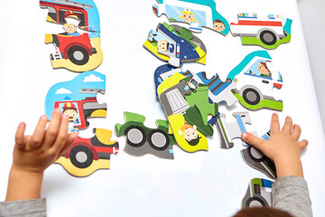 Fototapeta premium Child playing with puzzles,. The boy is playing in his room. Educational logic toys for kid's..