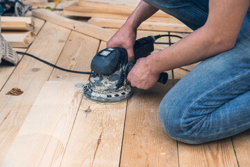 close up of a worker sanding wood planks with a grinder