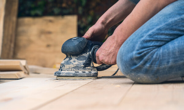 close up of a worker sanding wood planks with a grinder
