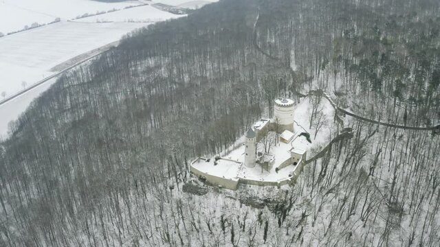 Drone aerial of the fairy tale castle Plesse in winter with a huge amount of snow on a beautiful mountain near Bovenden, Germany, Europe.