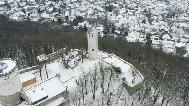 Drone aerial of the fairy tale castle Plesse in winter with a huge amount of snow on a beautiful mountain near Bovenden, Germany, Europe.