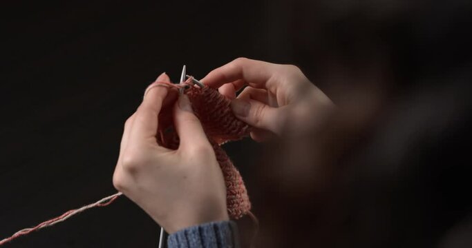 The woman knits on the needles with a double thread.