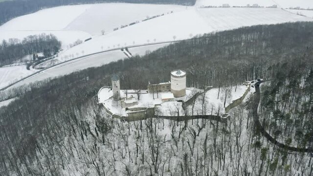 Drone aerial of the fairy tale castle Plesse in winter with a huge amount of snow on a beautiful mountain near Bovenden, Germany, Europe.