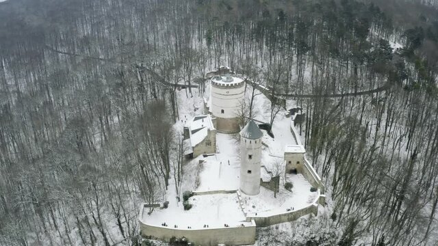 Drone aerial of the fairy tale castle Plesse in winter with a huge amount of snow on a beautiful mountain near Bovenden, Germany, Europe.