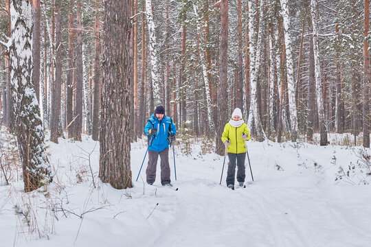 Mature Couple In Winter Sportswear Are Skiing In Snowy Forest.