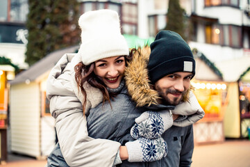 Young lovely couple bride groom newlyweds standing street kissing hugging, spending time together, smiling happy joke. New Year Christmas decorations, Valentines Day concept.