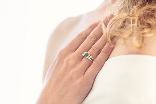 Detalle de novia llevando anillo de compromiso de esmeralda y diamantes