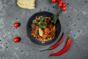 noodles with veal and vegetables on a gray table
