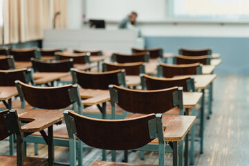 Wooden lecture chairs arranged in the classroom. Empty college classroom with many vintage wooden lecture chairs but no students. Back to school concept. 