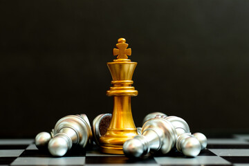 Gold king chess piece win over lying down silver pawn on black background