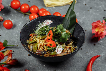 Stir-fried noodles and vegetables, in black bowl. Delicious, nutritious Asian food