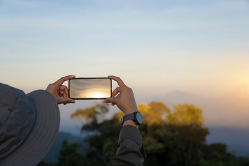 Rear of female use smartphone taking a photo at peak rock while travel in the winter
