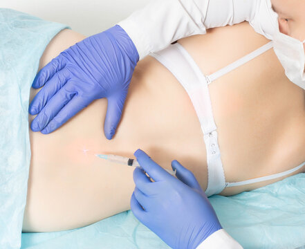 The doctor makes a paravertebral medical blockade in the lumbar spine for a girl patient. The concept of pain relief for diseases of the spine and infringement of the sciatic nerve