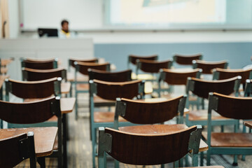 Wooden lecture chairs arranged in the classroom. Empty college classroom with many vintage wooden lecture chairs but no students. Back to school concept. 