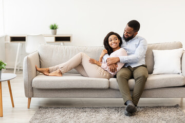 African american couple spending weekend together lying on couch