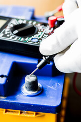 checking the charge of a car battery with a multimeter at a service station