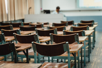 Wooden lecture chairs arranged in the classroom. Empty college classroom with many vintage wooden lecture chairs but no students. Back to school concept. 