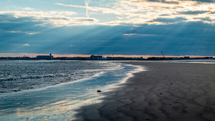 Sun rays shine through the clouds at dusk over the Stone Harbor beach in New Jersey