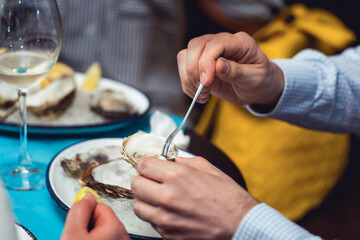 man eating oyster shellfish in a seafood restaurant. yellow toning, selective focus
