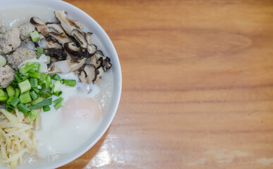 Pork porridge with eggs placed on a wooden table.