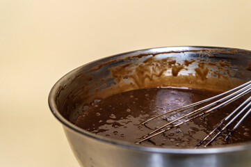 chocolate dough in a steel bowl and steel whisk close up