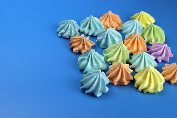Colored meringues on a blue background. Desert, sweets, cake shop concept. Selective focus