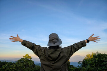 Rear freedom woman open arms at mountain peak