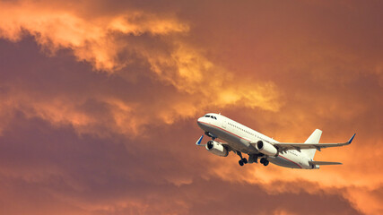 Fototapeta na wymiar Zoom photo of airplane taking off at beautiful sunset with golden colours