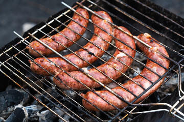 cooking sausages on the grill in the barbecue outdoors on a picnic