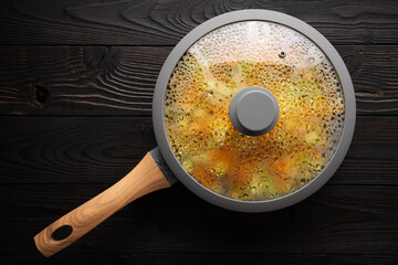 fresh stewed vegetables in a frying pan on a wooden background, flat lay