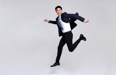 Fototapeta na wymiar Fun portrait of happy energetic young Asian businessman jumping in mid-air isolated on studio white background.