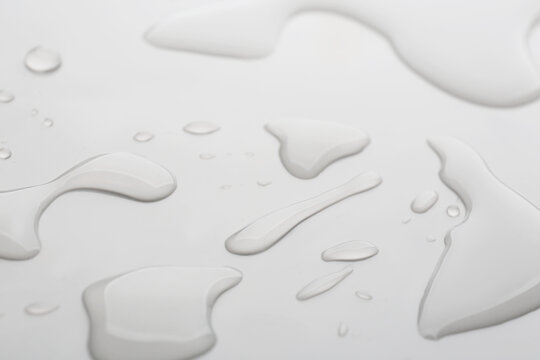 Drops of spilled water on grey background, closeup