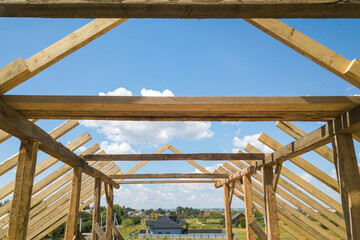 Aerial view of unfinished house with wooden roof frame structure under construction.