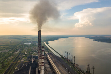 Aerial view of high chimney pipes with grey smoke from coal power plant. Production of electricity with fossil fuel.