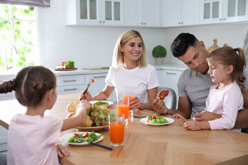 Happy family having breakfast together at table in modern kitchen